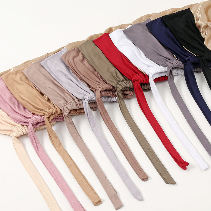 Flat lay of multiple Zeenah Silk Undercaps in assorted shades, arranged side by side with long tie straps displayed.
