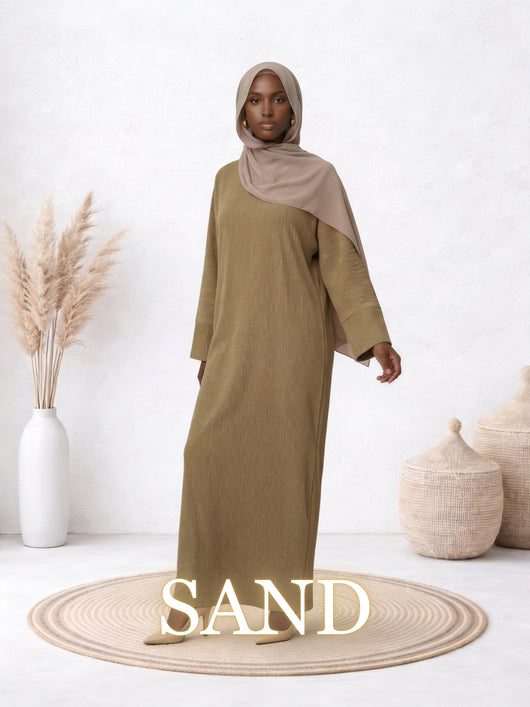 Full-length view of the Amanah Abaya in Sand, worn with a neutral hijab in a minimalist studio setting.