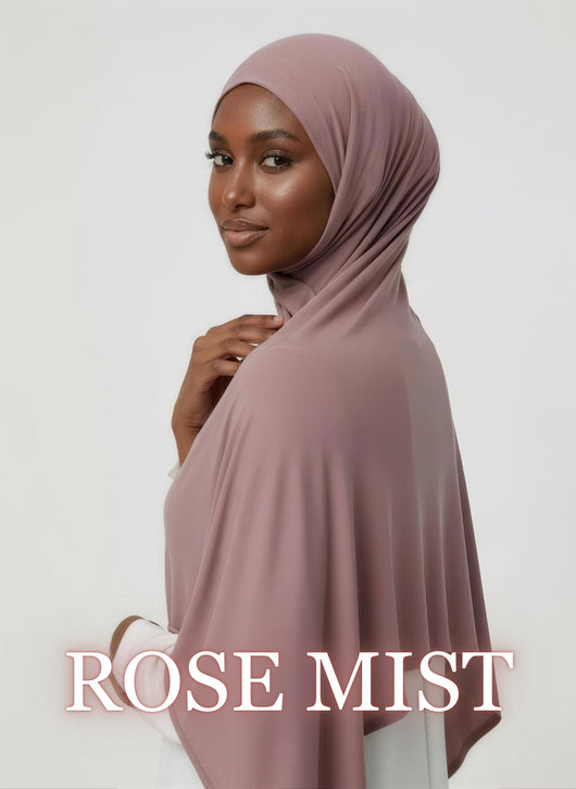 Woman wearing rose mist NurAmaya™ modal hijab with soft elegant drape in white studio