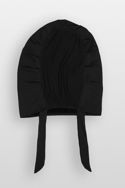 Flat lay of black Amina velvet hold undercap with mesh back and adjustable tie-back in white studio