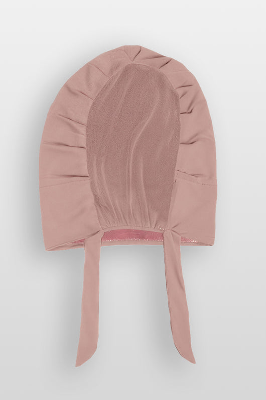Flat lay of blush pink Amina velvet hold undercap with mesh back and adjustable tie-back in white studio

