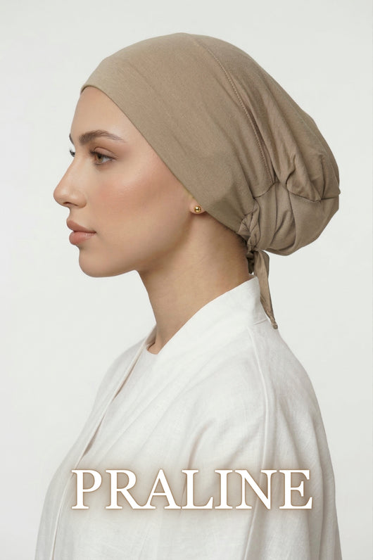 Side profile of model wearing praline Amina undercap with mesh back and adjustable tie-back