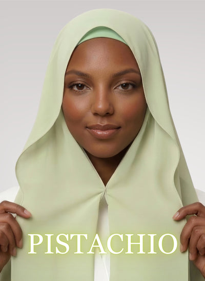Woman wearing pistachio green NurAmira instant chiffon hijab with front panels held by magnets and smooth drape in white studio