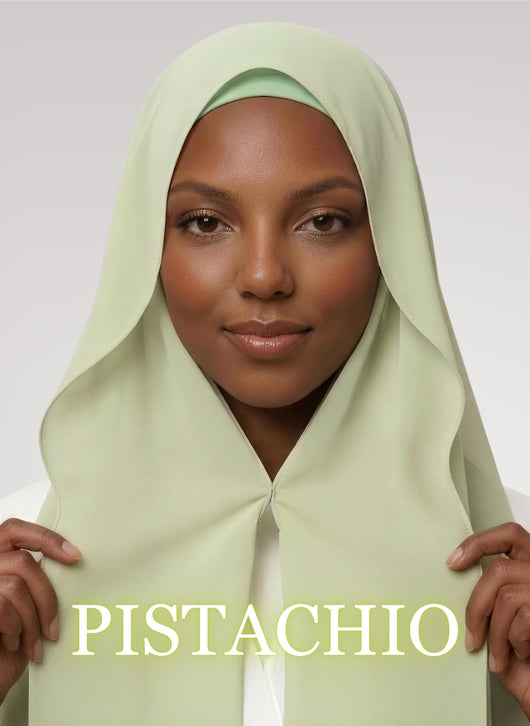 Woman wearing pistachio green NurAmira instant chiffon hijab with front panels held by magnets and smooth drape in white studio