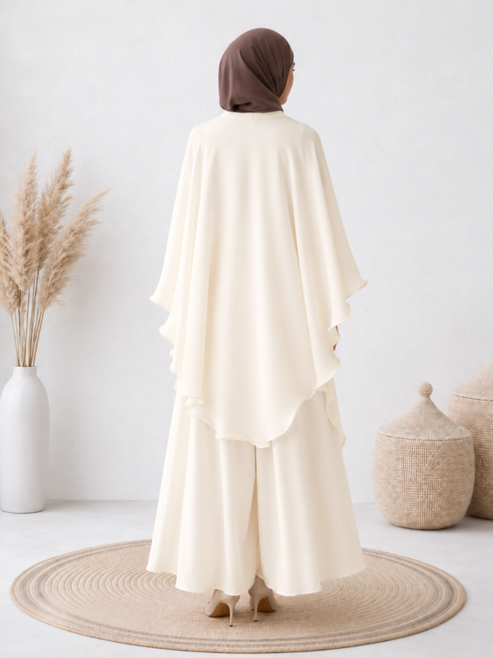 Back view of the pleated cape with a flowing silhouette.