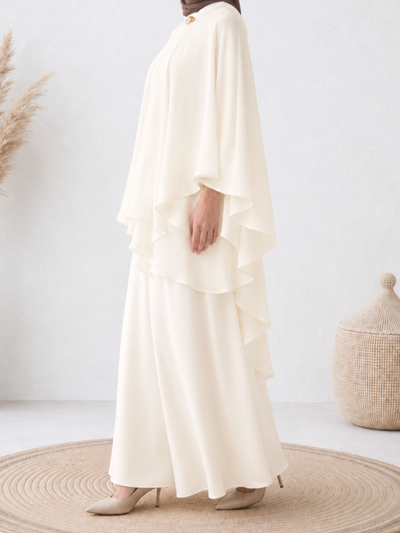 Side view of the pleated cape showing its layered drape.
