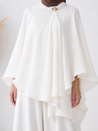 Close-up of the Elara™ Pleated Cape Set, featuring the finely pleated fabric, gold brooch fastening, and cascading layered cape design.