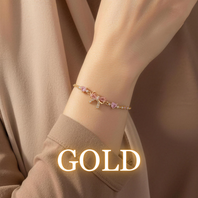 Gold Lulya bracelet with pink bow charm styled with warm neutral sleeves