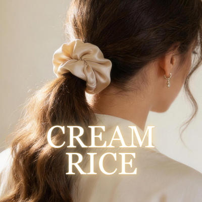A woman wearing a cream rice satin scrunchie with soft brown ponytail, white background