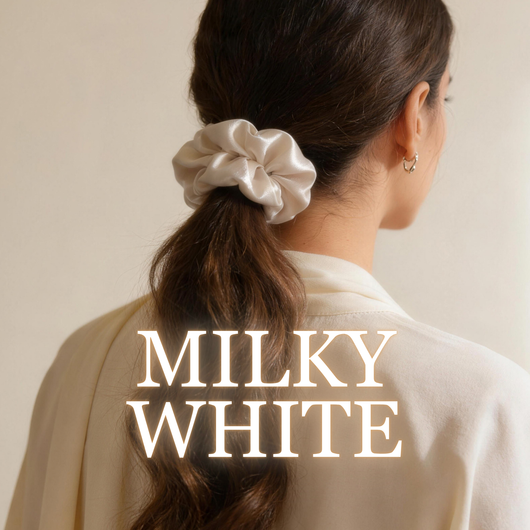 A woman wearing a milky white satin scrunchie with long brunette ponytail, white background