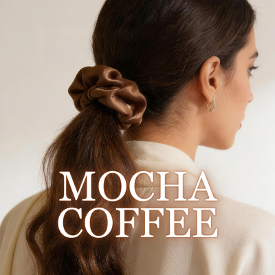 A woman wearing a mocha coffee satin scrunchie with dark wavy brown hair, white background