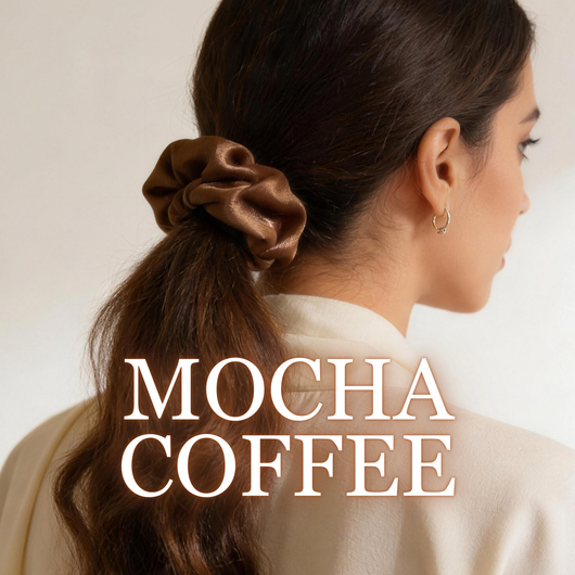 A woman wearing a mocha coffee satin scrunchie with dark wavy brown hair, white background