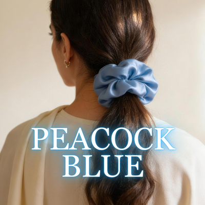 A woman wearing a peacock blue satin scrunchie with soft brunette ponytail, white background