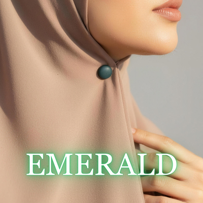 Close-up of a model wearing a light beige hijab secured under the chin with a matte deep emerald green magnet, with the text "EMERALD" overlaid at the bottom.
