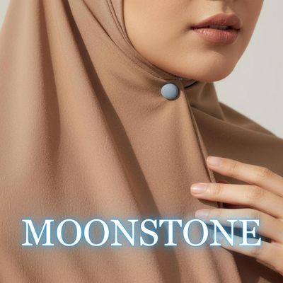 Close-up of a model wearing a warm brown hijab secured under the chin with a matte slate blue-gray "Moonstone" magnet, with the text "MOONSTONE" overlaid at the bottom.