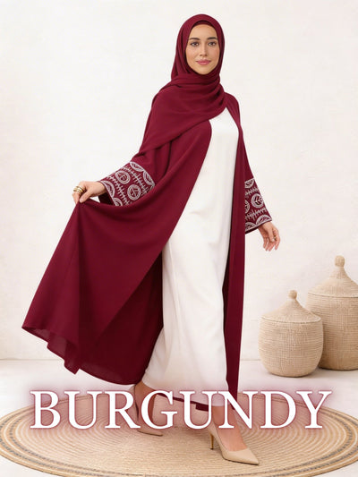 Woman wearing Nour abaya in burgundy with flowing drape and embroidered cuffs