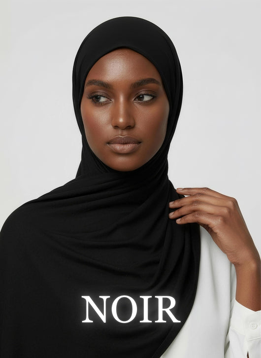 Woman wearing noir NurAmaya™ modal hijab with sleek smooth drape in white studio