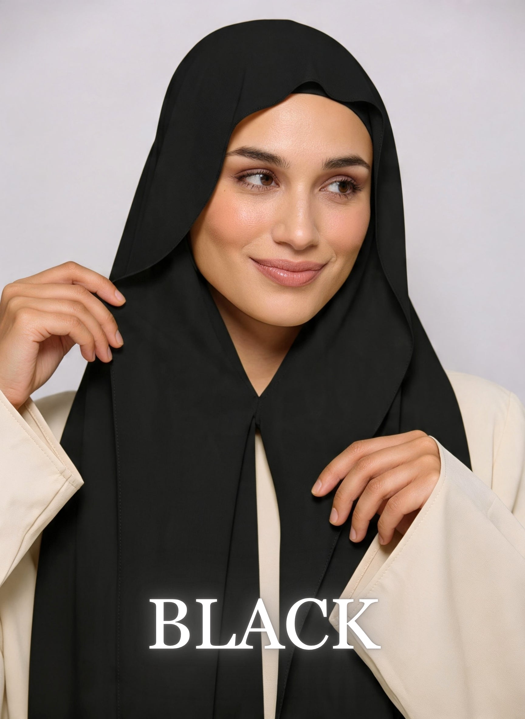 Woman wearing black NurAmira instant chiffon hijab with front panels held by magnets and smooth drape in white studio