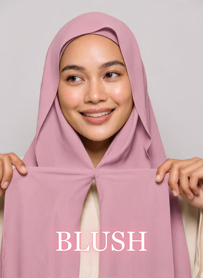 Woman wearing blush pink NurAmira instant chiffon hijab with front panels held by magnets and smooth drape in white studio