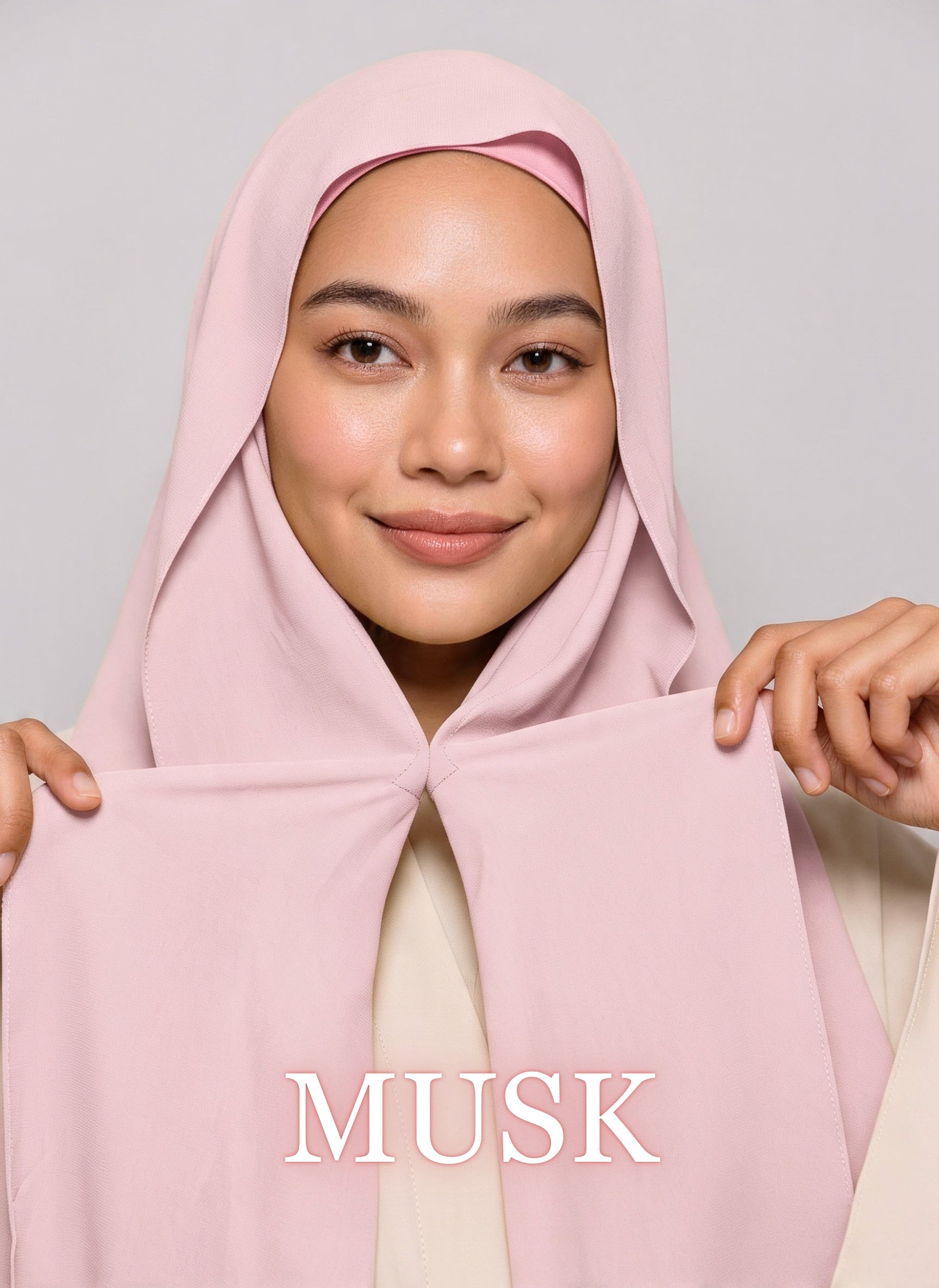 Woman wearing musk pink NurAmira instant chiffon hijab with front panels held by magnets and smooth drape in white studio