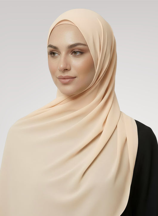 Hijabi model wearing shell beige Nuramira chiffon hijab with smooth layered drape in white studio