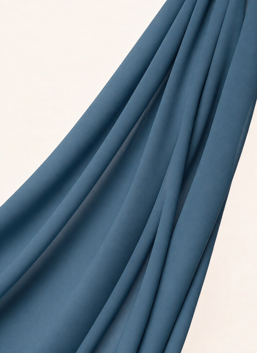 Close-up of NurAmira Instant Chiffon Hijab fabric texture in Bahr deep teal-blue shade, soft draped folds.