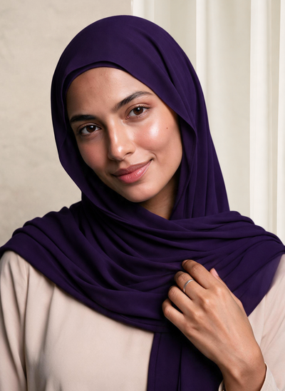 Woman wearing NurAmira Instant Chiffon Hijab in Iris deep purple shade, draped over shoulder style.