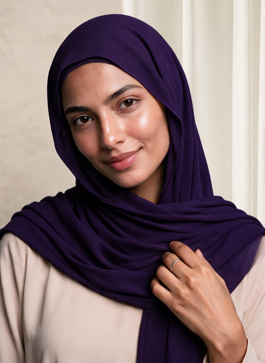 Woman wearing NurAmira Instant Chiffon Hijab in Iris deep purple shade, draped over shoulder style.