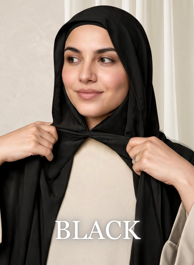 Woman wearing the NurAmira™ Instant Chiffon Hijab in Black, gently holding the front scarf beneath the chin.
