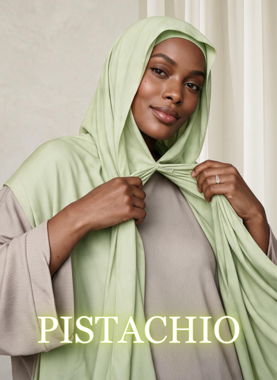 Woman wearing NurAmira™ Instant Chiffon Hijab in Pistachio, holding the front drape.