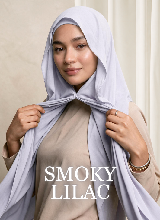 Woman wearing NurAmira™ Instant Chiffon Hijab in Smoky Lilac, holding the hijab beneath her chin.