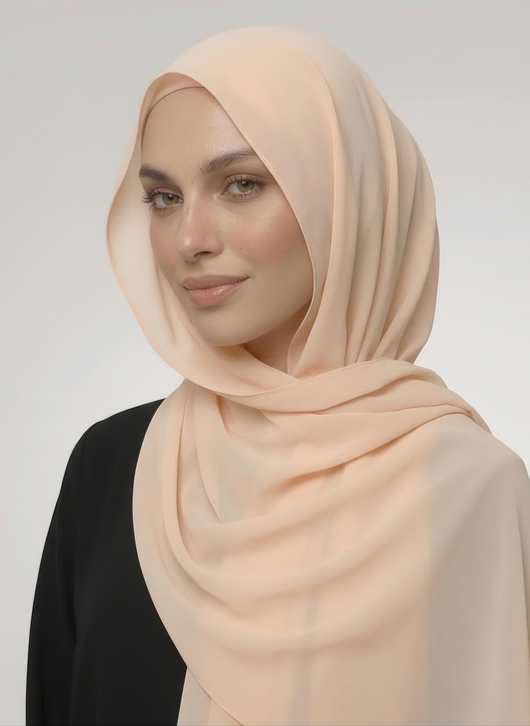 Hijabi woman wearing shell beige NurAmira instant chiffon hijab with soft drape over the shoulder and secure undercap in white studio