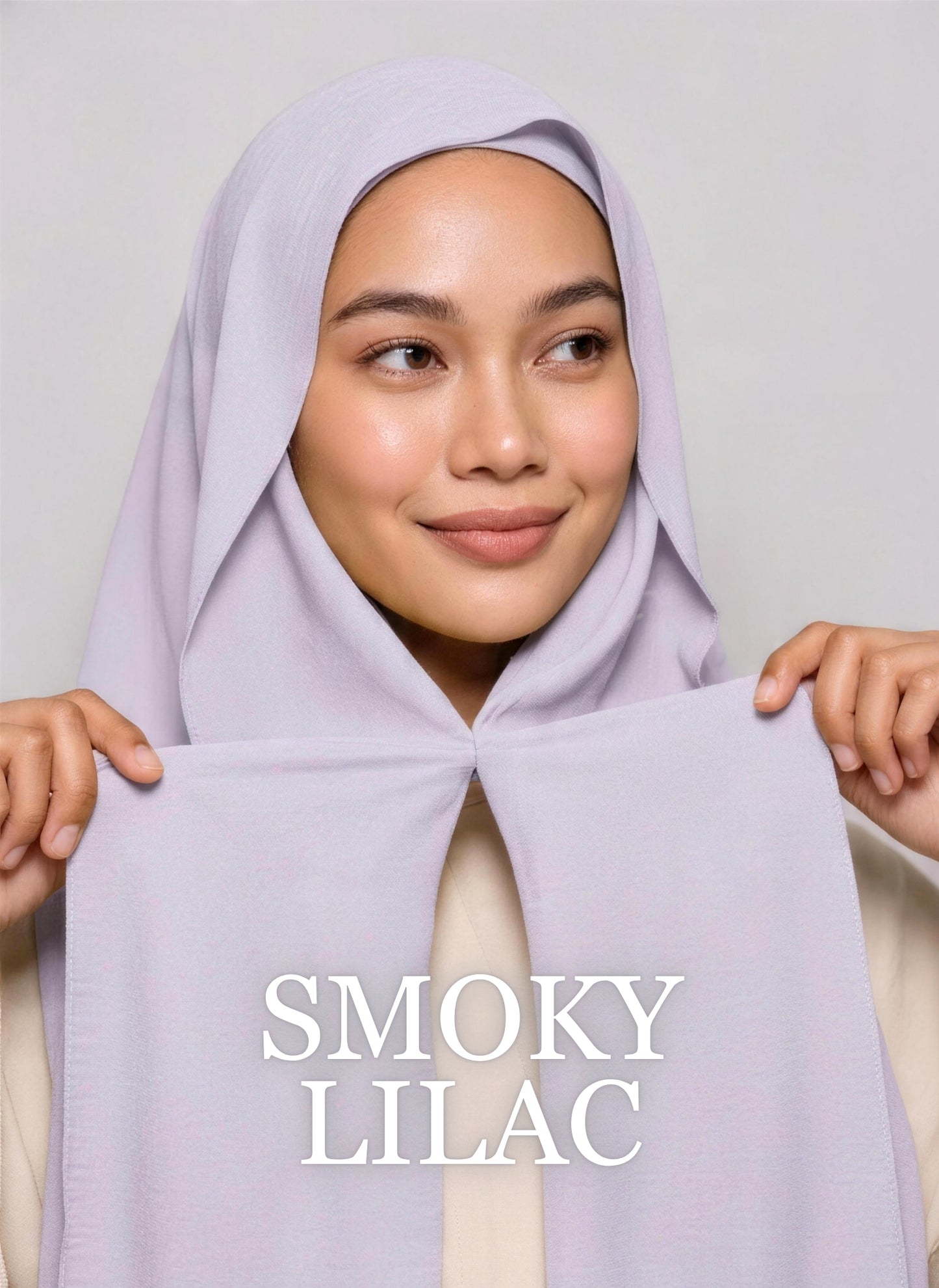 Woman wearing greyish purple NurAmira instant chiffon hijab with front panels held by magnets and smooth drape in white studio