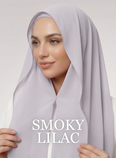Woman wearing greyish purple NurAmira instant chiffon hijab with front panels held by magnets and smooth drape in white studio