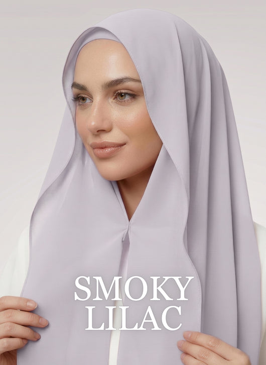 Woman wearing greyish purple NurAmira instant chiffon hijab with front panels held by magnets and smooth drape in white studio