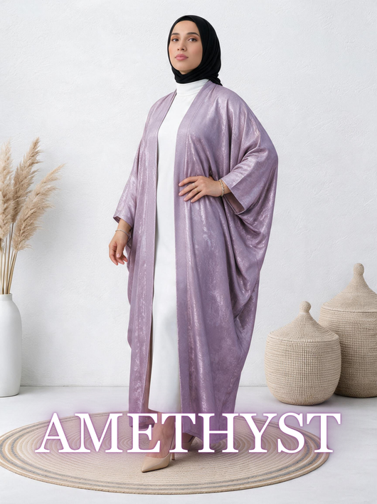 Woman wearing Safiya Abaya in Amethyst shimmer lilac, open kimono-style over white dress.
