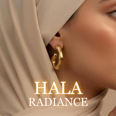 Woman wearing Hala gold earrings with beige hijab in soft warm lighting