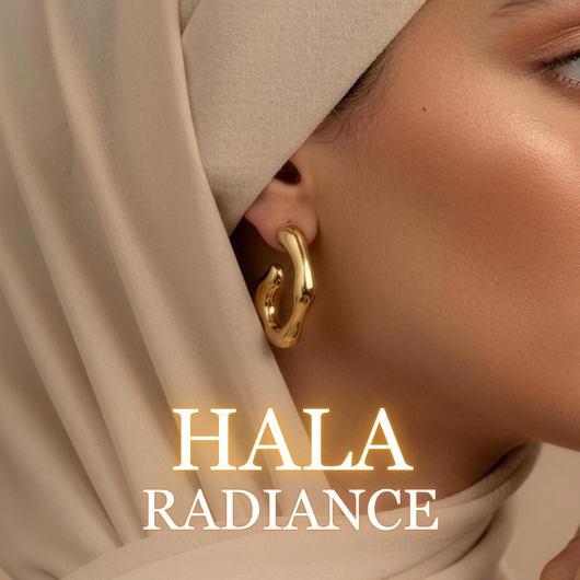 Woman wearing Hala gold earrings with beige hijab in soft warm lighting