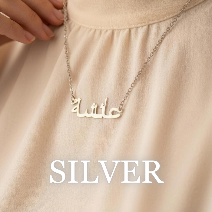 Woman wearing Zahria silver Arabic name necklace on soft neutral fabric