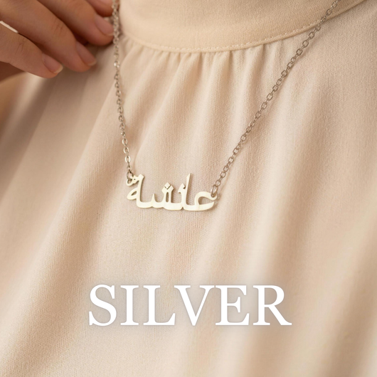 Woman wearing Zahria silver Arabic name necklace on soft neutral fabric
