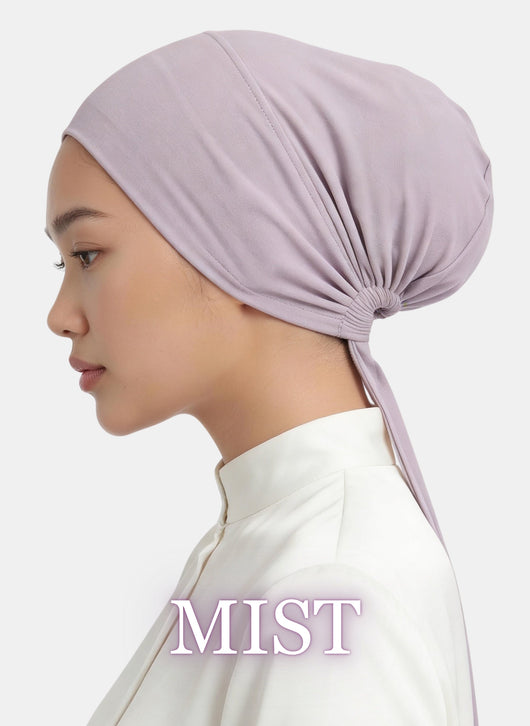 Side profile of a model wearing the Zeenah Silk Undercap in Mist, featuring a soft lilac shade and tie-back design.